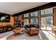 Inviting living room with a brick fireplace, wood-paneled walls, large windows and comfortable seating at 25257 Snyder Ave, Conifer, CO 80433