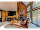 Inviting living room with a brick fireplace, wood-paneled walls, large windows and comfortable seating at 25257 Snyder Ave, Conifer, CO 80433