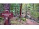 Sign for Neighborhood Access along trail through wooded area; bridge visible at 25257 Snyder Ave, Conifer, CO 80433