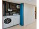 Convenient laundry room with washer and dryer, storage shelves, and a blue door at 2891 W Long Dr # D, Littleton, CO 80120
