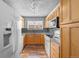 Galley kitchen with light wood cabinets and appliances at 3656 S Depew St # 104, Denver, CO 80235