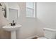 Powder room features pedestal sink, toilet, and window with natural light at 3464 N Irvington St, Aurora, CO 80019