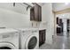 Bright laundry room features updated washer and dryer, storage cabinets, and sink at 9772 Taylor River Cir, Littleton, CO 80125