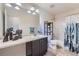 Neutral bathroom with a dark vanity, large mirror, shower/tub with curtain, and a tiled floor at 25097 E Lake Dr, Aurora, CO 80016