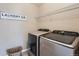 Functional laundry room with modern washer and dryer units, wire shelving, and a woven basket at 25097 E Lake Dr, Aurora, CO 80016