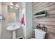 Charming powder room featuring decorative wood paneling, a pedestal sink, and rustic accents at 25097 E Lake Dr, Aurora, CO 80016