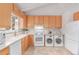 Bright kitchen featuring matching washer and dryer, wood cabinets, and tile floors at 1005 S Miller Way, Lakewood, CO 80226