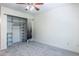Bright bedroom featuring neutral carpet, a ceiling fan, and a closet with adjustable shelving at 703 S Depew St, Lakewood, CO 80226