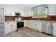 Updated kitchen with stainless steel appliances, stone backsplash, and white cabinets at 9821 Bucknell Ct, Highlands Ranch, CO 80129