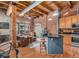Open-concept living room with exposed brick, wooden beams, and modern kitchen island at 2960 Inca St # 317, Denver, CO 80202