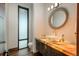 Chic powder room featuring unique lighting, an eye-catching mirror, and a vessel sink on a stone countertop at 5140 S Kearney Ct, Greenwood Village, CO 80111