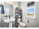 Modern half bathroom featuring a pedestal sink, toilet, and a window with a pleasant outdoor view at 21413 E 59Th Pl, Aurora, CO 80019