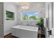 Bright bathroom featuring a modern soaking tub and a view of the outdoors at 2485 S Fillmore St, Denver, CO 80210