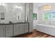 Bright bathroom featuring double sinks, a soaking tub, and marble-look tile at 2485 S Fillmore St, Denver, CO 80210