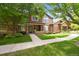 Inviting exterior of brick home featuring a covered porch, mature trees, and manicured lawn at 6404 Silver Mesa Dr # E, Highlands Ranch, CO 80130