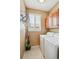 A functional laundry room with a washer, dryer, upper cabinets, and window with shutters at 6404 Silver Mesa Dr # E, Highlands Ranch, CO 80130