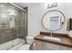 Bathroom features a shower over bath, a large round mirror and a wooden cabinet sink at 8565 E 50Th Dr, Denver, CO 80238