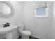 Clean half bathroom with a pedestal sink, a modern faucet, and a round mirror hanging on the wall at 1041 W Witherspoon Dr, Elizabeth, CO 80107
