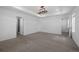 Large bedroom featuring neutral carpet, tray ceiling, and adjoining bathroom and walk-in closet at 1041 W Witherspoon Dr, Elizabeth, CO 80107