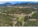 Wide aerial perspective of a home on acreage, with a barn, pond, and surrounding wooded area at 27436 Kennedy Gulch Rd, Conifer, CO 80433