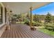 Covered porch with BBQ grill overlooks grassy yard and mature trees at 27436 Kennedy Gulch Rd, Conifer, CO 80433