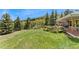 Spacious back yard with lawn and trees adjoins the brick home's multiple decks at 27436 Kennedy Gulch Rd, Conifer, CO 80433