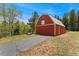 Exterior view of a well-maintained red barn with a paved driveway and surrounding trees at 27436 Kennedy Gulch Rd, Conifer, CO 80433