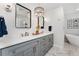 Double vanity featuring white countertops, gray cabinetry, contemporary mirrors, sconces and marble-look flooring at 27436 Kennedy Gulch Rd, Conifer, CO 80433