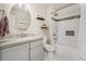 Bright bathroom with a gray vanity, round mirror, and a shower-tub combination with a white subway tile surround at 27436 Kennedy Gulch Rd, Conifer, CO 80433