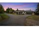 A ranch-style home featuring a two-car garage, lush landscaping, and scenic evening skies at 27436 Kennedy Gulch Rd, Conifer, CO 80433