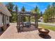 An inviting brick patio featuring a pergola, dining set, and a cozy fire pit with seating at 27436 Kennedy Gulch Rd, Conifer, CO 80433