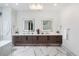 Luxurious bathroom featuring double vanity with light-up mirrors and sleek fixtures, plus gorgeous marble-style flooring at 2495 Red Hawk Pl, Broomfield, CO 80023
