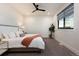 A modern bedroom with neutral tones, a ceiling fan, a large window, and cozy décor at 2495 Red Hawk Pl, Broomfield, CO 80023