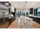 Modern kitchen with hardwood floors, black cabinets, stainless appliances, and waterfall island, open to living room at 2495 Red Hawk Pl, Broomfield, CO 80023