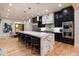 A modern kitchen features black cabinets, stainless appliances, pendant lights, and a waterfall island with bar stools at 2495 Red Hawk Pl, Broomfield, CO 80023