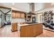 Bright kitchen with wood cabinetry, stainless steel appliances, and a large center island with a cooktop at 6663 S Prescott Way, Littleton, CO 80120