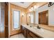 Bathroom featuring dual sinks, wood paneled walls, and plenty of counter space at 1579 W Briarwood Ave, Littleton, CO 80120