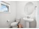 A white bathroom features a pedestal sink, toilet, and window allowing for plenty of natural light at 10983 Uvalda St, Commerce City, CO 80022