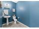 Stylish powder room with blue walls features a modern pedestal sink and a coordinating toilet at 12860 Jasmine St # C, Thornton, CO 80602