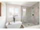 Modern bathroom with soaking tub and walk-in shower with glass enclosure, black fixtures, and neutral tiling at 2571 S Cherokee St, Denver, CO 80223