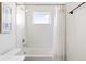 Clean white bathroom featuring subway tiles, a tub with shower, and a small window for natural light at 2571 S Cherokee St, Denver, CO 80223