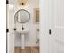 Stylish powder room features pedestal sink, round mirror, updated lighting, and white paneled doors at 2571 S Cherokee St, Denver, CO 80223