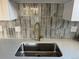 Close up of the modern kitchen sink with quartz countertops, stylish tile backsplash, and a gold faucet at 9695 E Kansas Cir # 44, Denver, CO 80247