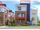 Modern townhome featuring brick facade, balcony, black accents, and orange decorative elements, with a manicured lawn at 3030 Wilson Ct # 5, Denver, CO 80205
