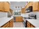 Well-appointed kitchen showcasing stainless appliances, white counters, and wood cabinetry at 9320 W Ontario Dr, Littleton, CO 80128