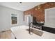 Bright kitchen with white countertops, stainless steel appliances, and a rustic brick accent wall at 3817 Osage St, Denver, CO 80211