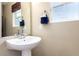 Well-lit half-bathroom featuring a pedestal sink, mirror, and window with a brown shade at 5570 Perth Ct, Denver, CO 80249