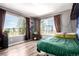 Bedroom featuring large windows, green bedding, and hardwood floors at 5570 Perth Ct, Denver, CO 80249