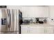 Kitchen featuring stainless steel refrigerator, microwave, and coffee maker on white countertops and cabinets at 5570 Perth Ct, Denver, CO 80249