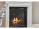 Close-up of a fireplace with a white mantel and black screen showcasing burning logs and creating a cozy atmosphere at 5471 W 97Th Pl # E, Broomfield, CO 80020